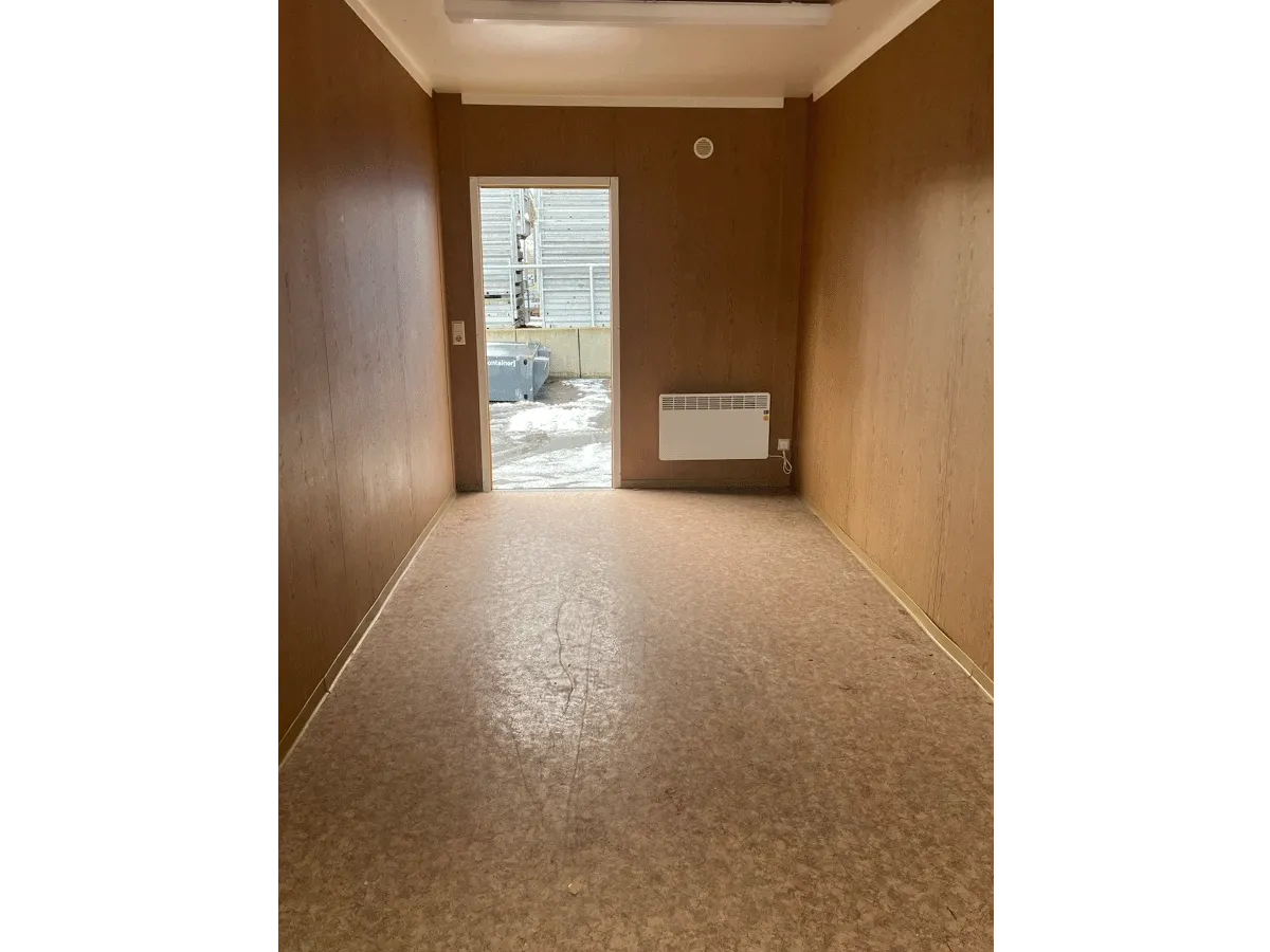 Gebrauchter 20 Fuß Bürocontainer Innenansicht mit Glastür, Konvektorheizung und Deckenleuchte – Blick zum Ausgang