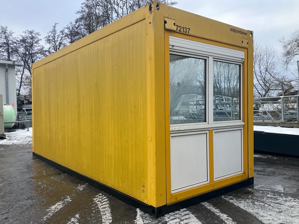 Gebrauchter 20 Fuß Bürocontainer gelb mit großem Fensterelement und Rolllade – Frontansicht im Winter mit Schnee