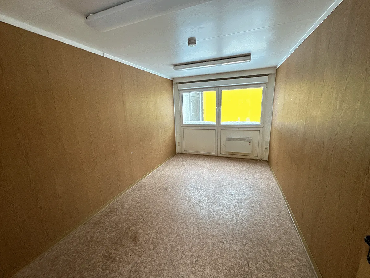 Innenansicht des gelben Bürocontainers mit Fokus auf den großzügigen Raumeindruck durch 3m Sonderbreite.