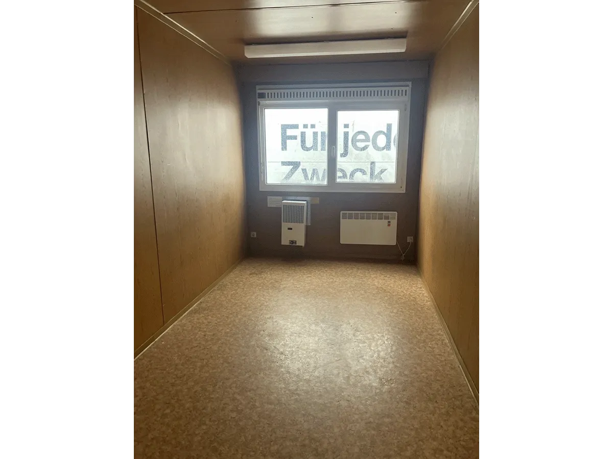 Gebrauchter 20 Fuß Bürocontainer Innenansicht mit Fenster, Klimagerät und Konvektorheizung – Blick zur Fensterseite