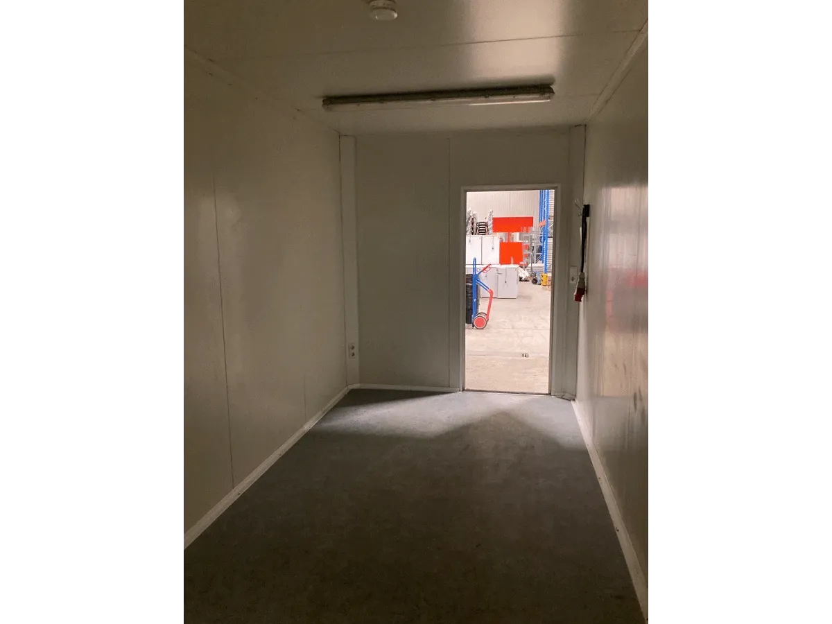 Gebrauchter Bürocontainer Innenraum mit Deckenleuchte und offener Tür Blick nach außen