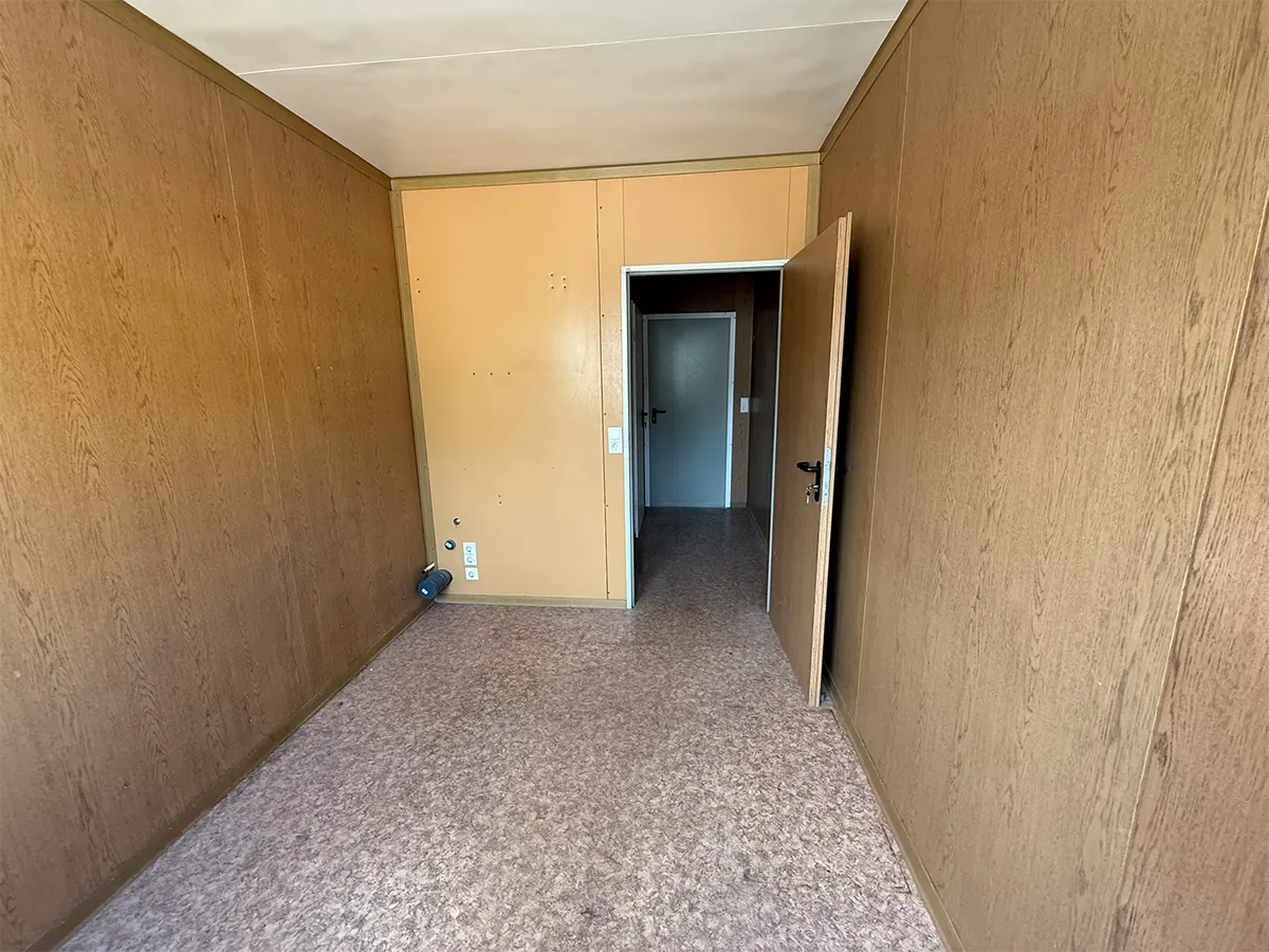 Gebrauchter Bürocontainer Innenansicht mit Holzpaneelen und Durchgang zum WC-Bereich