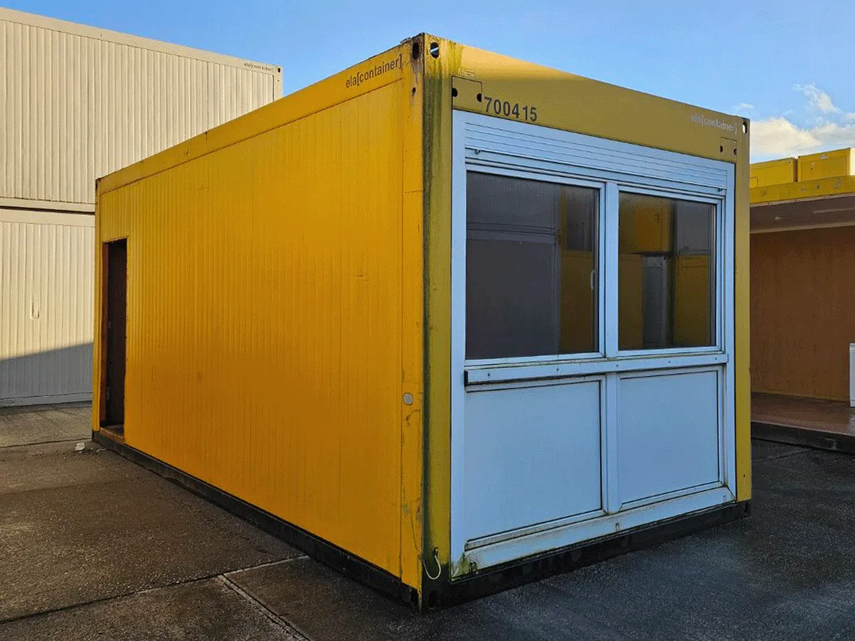Außenansicht eines gebrauchten gelben Bürocontainers in Sonderbreite mit Doppel-Fenster und Rollladen.