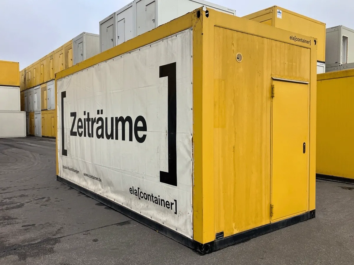 Gebrauchter 20 Fuß Bürocontainer gelb von ELA Container mit Werbebanner und Eingangstür – Rückansicht auf dem Containerplatz