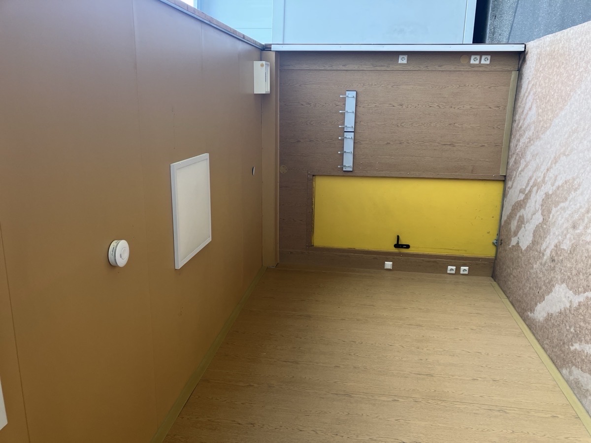 Gebrauchter 20 Fuß Bürocontainer Innenansicht mit gelber Eingangstür, Sicherungskasten, Steckdosen und Laminatboden – Blick von oben