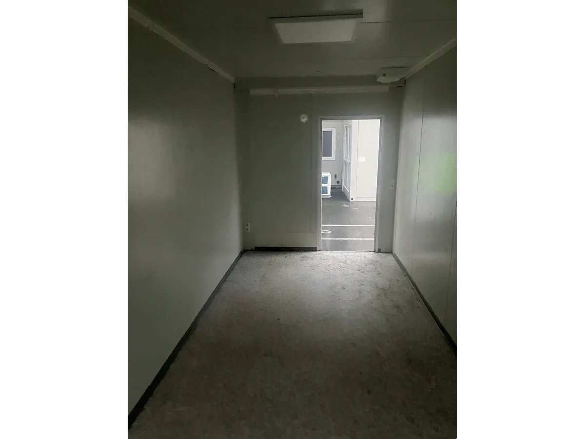 Gebrauchter Bürocontainer Innenraum mit Deckenleuchte und offener Eingangstür