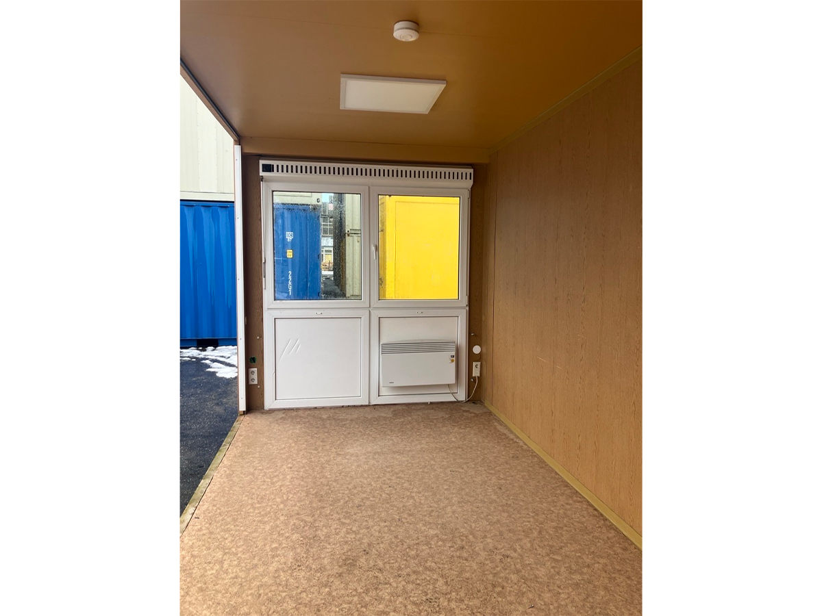Gebrauchter 20 Fuß Bürocontainer Innenansicht mit Glastür, Bewegungsmelder und Deckenleuchte – Blick Richtung Eingang