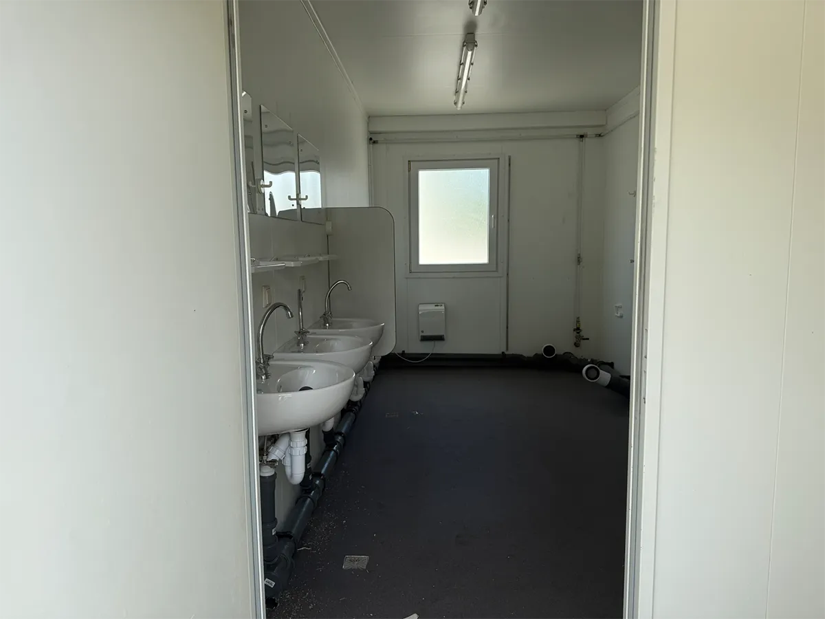 Gebrauchter Sanitärcontainer Innenansicht mit Waschbecken und Fenster