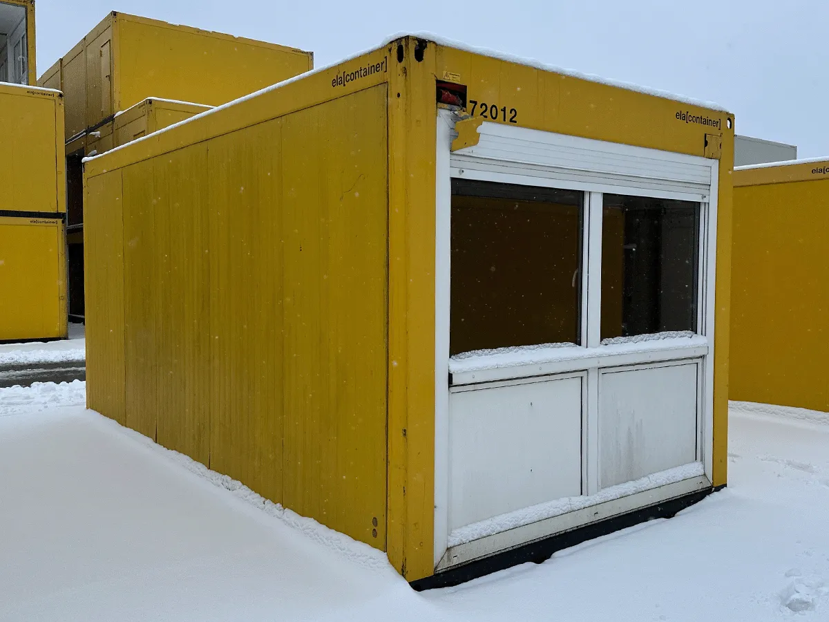 Gebrauchter 20 Fuß Bürocontainer gelb von ELA Container mit großem Fensterelement im Winter – Frontansicht mit Schnee